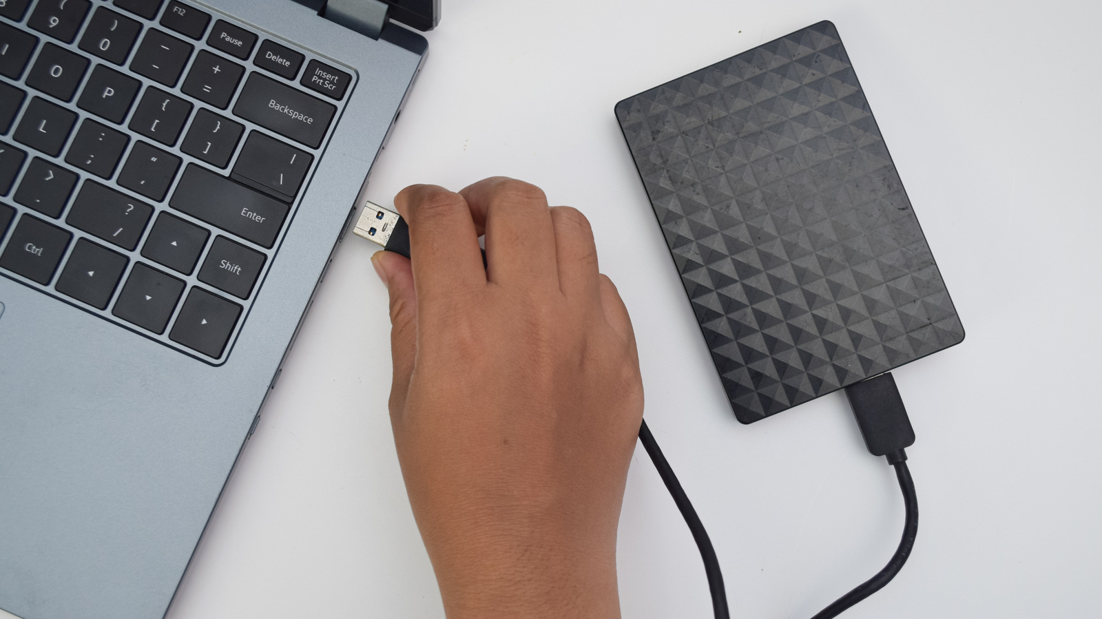 External hard drive resting on a desk beside a laptop